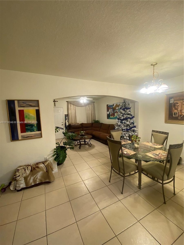 tiled dining area with a chandelier and a textured ceiling