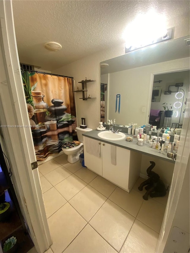 bathroom featuring tile patterned flooring, vanity, toilet, and a textured ceiling