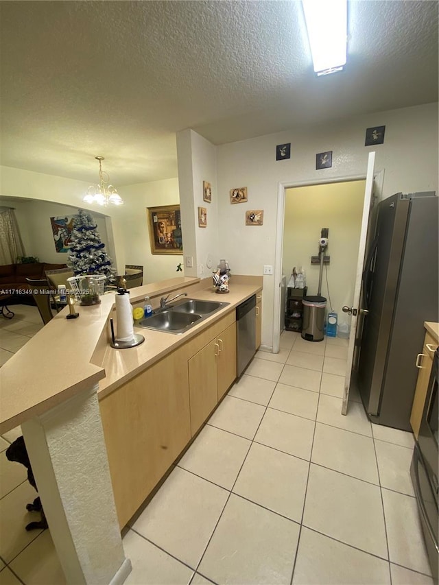 kitchen with a textured ceiling, stainless steel appliances, sink, a notable chandelier, and hanging light fixtures