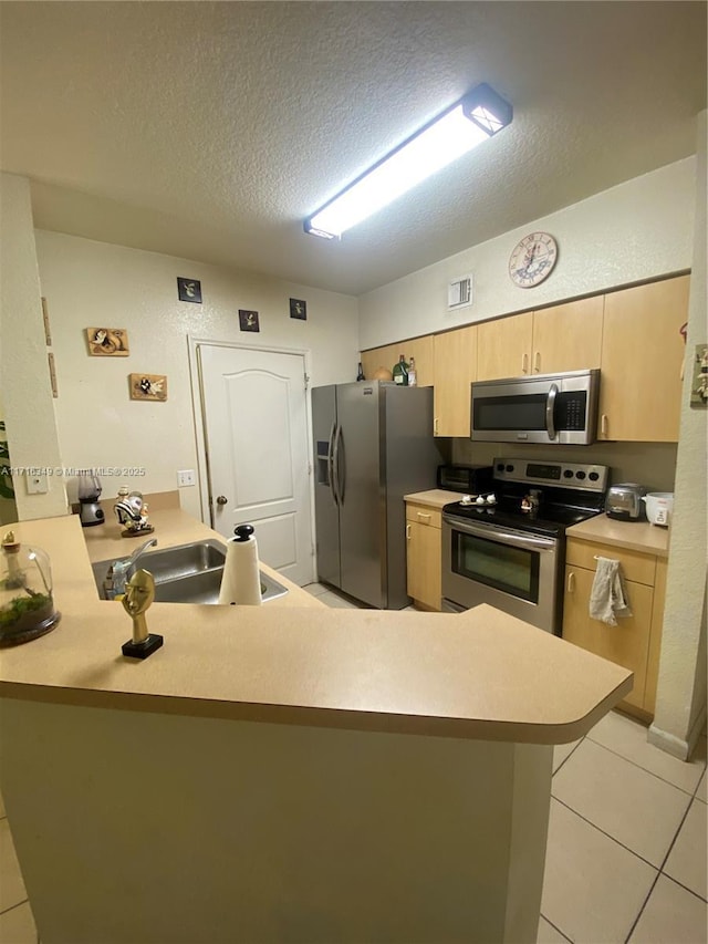 kitchen featuring kitchen peninsula, appliances with stainless steel finishes, a textured ceiling, sink, and light tile patterned flooring