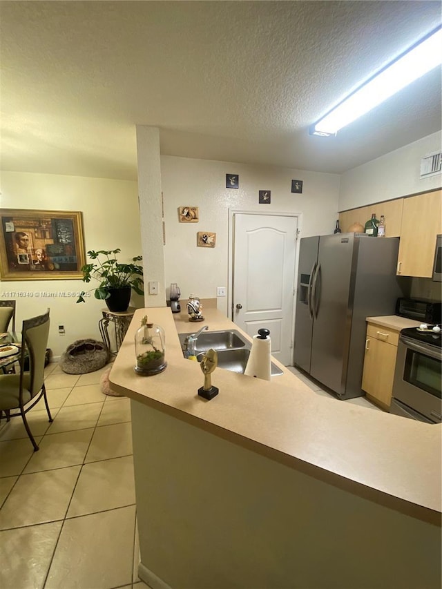 kitchen with sink, a textured ceiling, appliances with stainless steel finishes, light tile patterned flooring, and kitchen peninsula