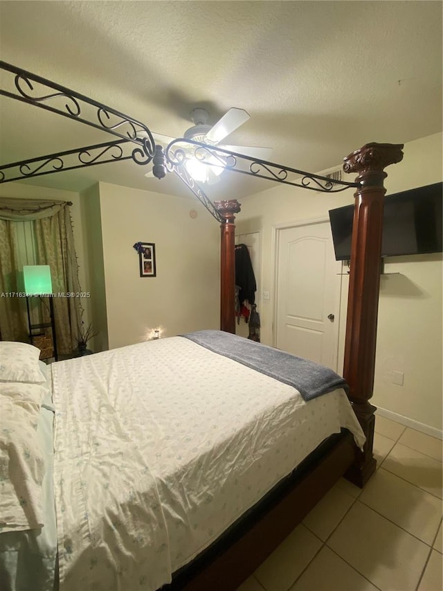 bedroom featuring ceiling fan, light tile patterned floors, and a textured ceiling