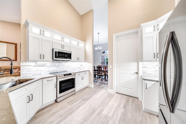 kitchen with backsplash, sink, white cabinets, and appliances with stainless steel finishes