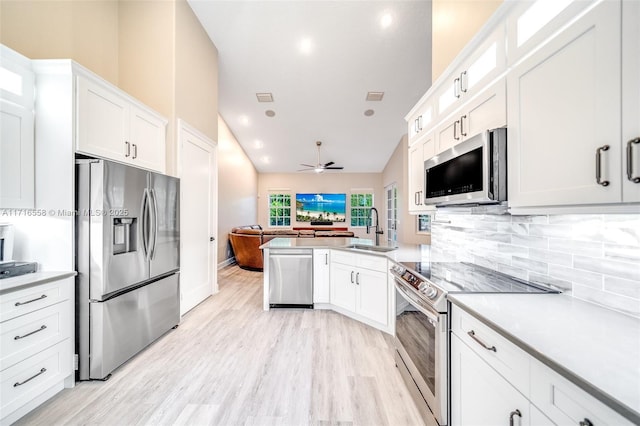 kitchen with ceiling fan, white cabinets, vaulted ceiling, and appliances with stainless steel finishes