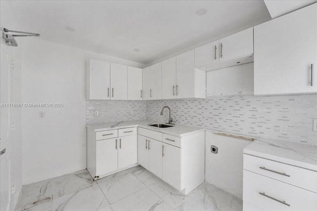 kitchen featuring backsplash, white cabinetry, sink, and light stone counters