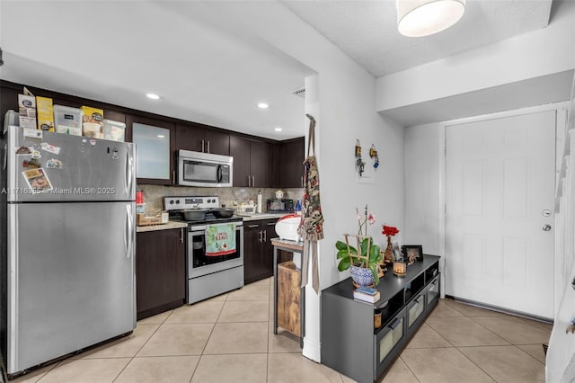 kitchen featuring tasteful backsplash, dark brown cabinetry, light tile patterned flooring, and appliances with stainless steel finishes