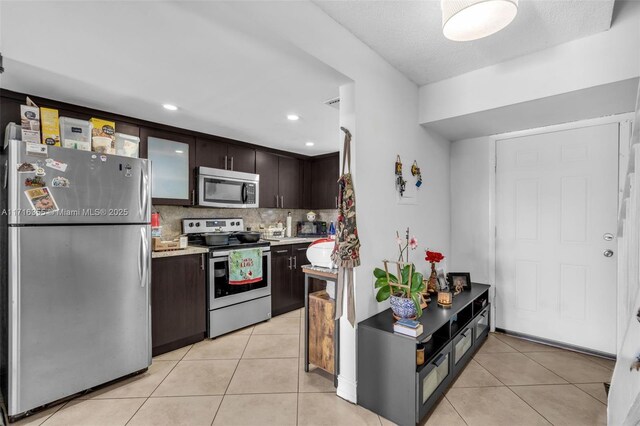 kitchen with stainless steel appliances, tasteful backsplash, dark brown cabinets, light countertops, and light tile patterned floors