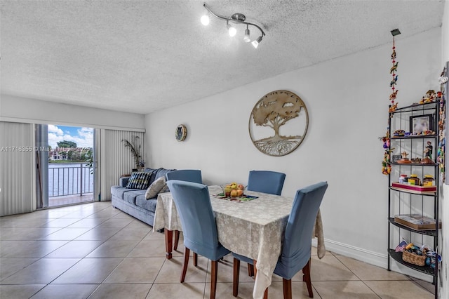 dining space featuring light tile patterned flooring, a textured ceiling, and baseboards