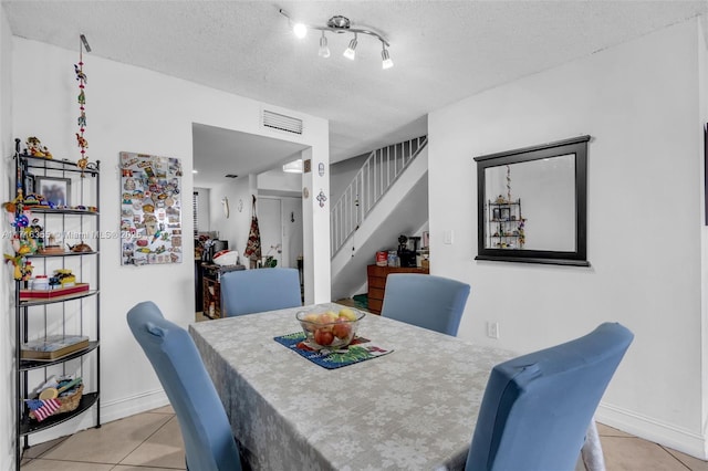 dining room with light tile patterned floors, visible vents, baseboards, stairway, and a textured ceiling