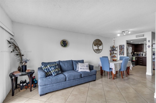 living room featuring light tile patterned flooring, a textured ceiling, and visible vents
