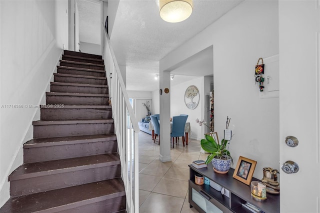 stairs with tile patterned flooring and a textured ceiling