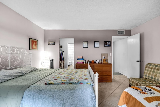 bedroom featuring a textured ceiling, visible vents, and tile patterned floors