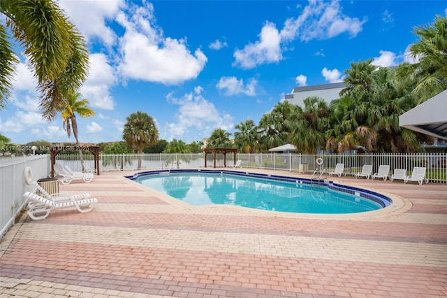 community pool with a patio area and fence