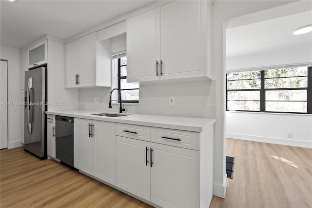 kitchen with stainless steel refrigerator with ice dispenser, light wood-type flooring, white cabinets, sink, and dishwasher