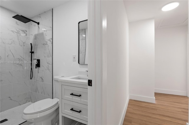 bathroom with tiled shower, wood-type flooring, vanity, and toilet