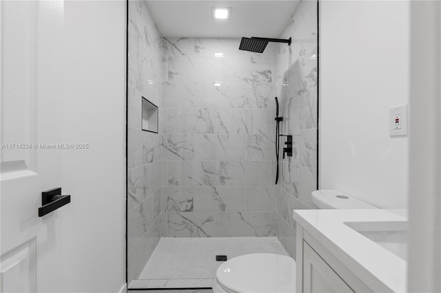 bathroom with vanity, toilet, and tiled shower