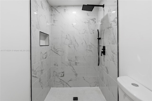 bathroom featuring tiled shower and toilet