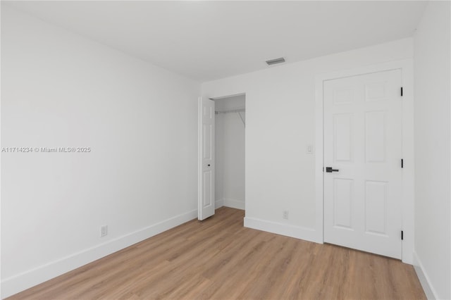 unfurnished bedroom with light wood-type flooring and a closet