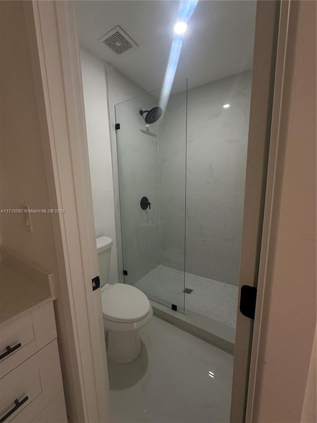 bathroom with vanity, toilet, and a tile shower