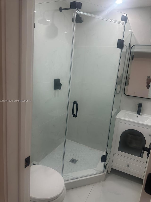 bathroom featuring vanity, a shower with shower door, and toilet