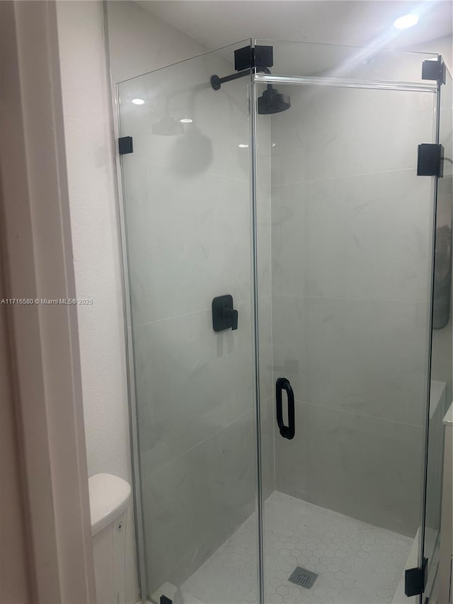 bathroom with toilet and a shower with shower door