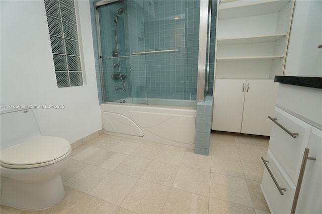 bathroom with toilet, enclosed tub / shower combo, vanity, tile patterned flooring, and baseboards