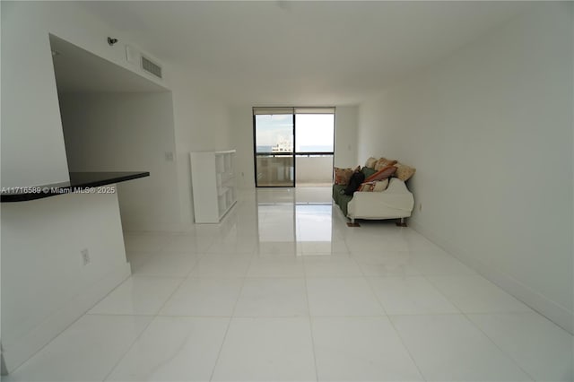 unfurnished living room featuring baseboards, expansive windows, visible vents, and light tile patterned flooring