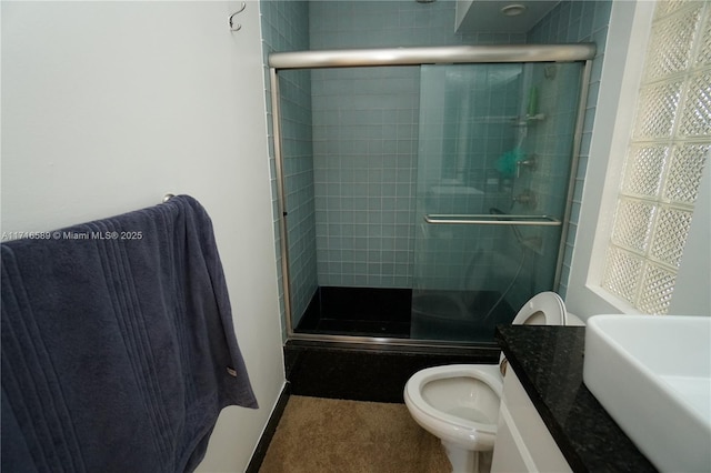 bathroom with a shower stall, toilet, and vanity