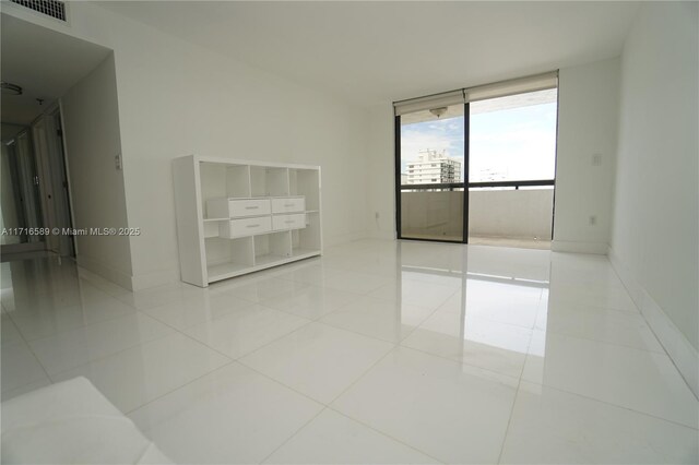 empty room with expansive windows and light tile patterned floors