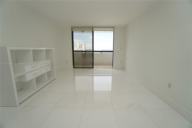 spare room with light tile patterned floors and a wall of windows