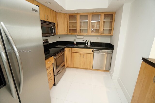 kitchen featuring appliances with stainless steel finishes, light tile patterned floors, light brown cabinetry, and sink