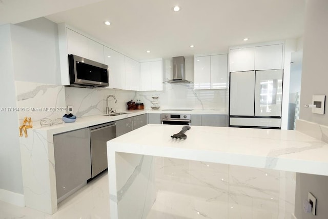 kitchen featuring stainless steel appliances, a sink, white cabinetry, modern cabinets, and wall chimney range hood