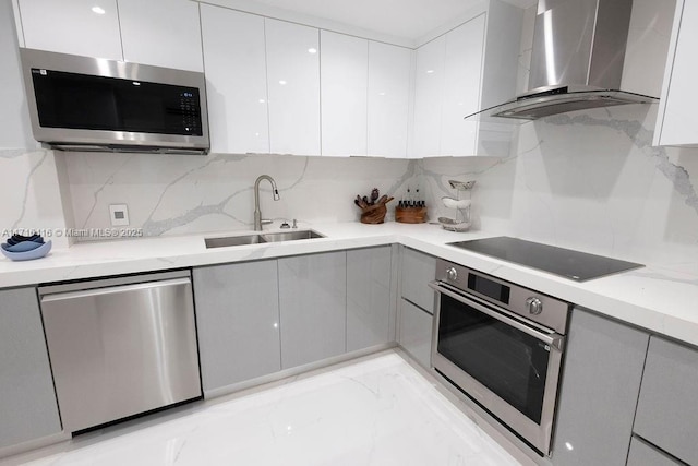 kitchen with gray cabinetry, backsplash, sink, wall chimney exhaust hood, and stainless steel appliances