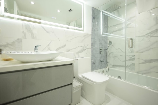 bathroom featuring tile walls, vanity, enclosed tub / shower combo, and toilet