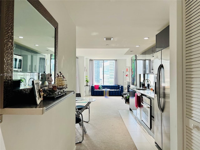 kitchen with a kitchen breakfast bar, sink, light colored carpet, and stainless steel appliances