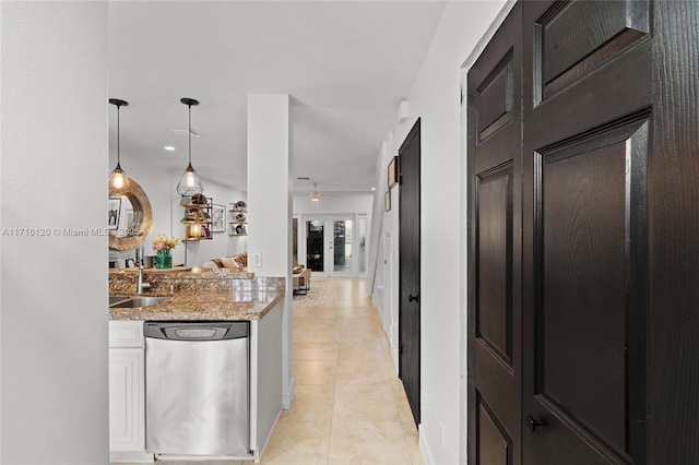 kitchen featuring light stone countertops, sink, stainless steel dishwasher, pendant lighting, and light tile patterned floors