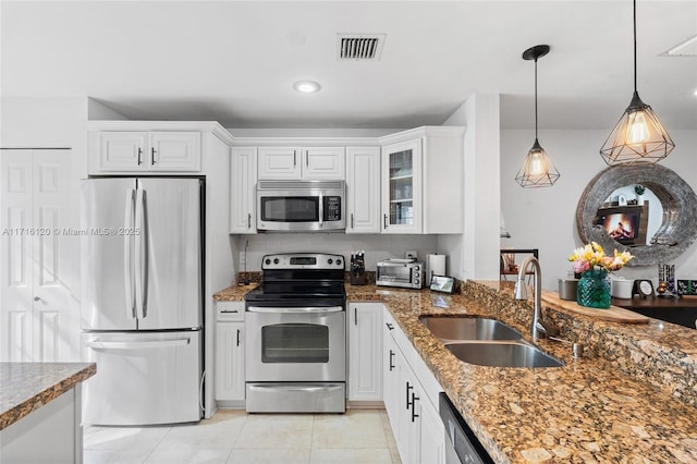 kitchen featuring sink, hanging light fixtures, dark stone countertops, white cabinets, and appliances with stainless steel finishes