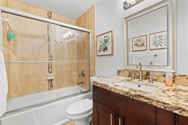 full bathroom with combined bath / shower with glass door, vanity, and toilet