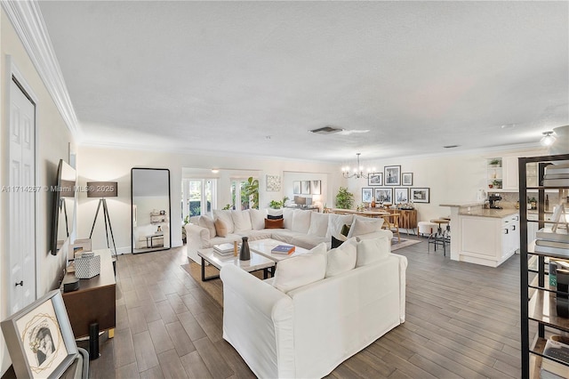 living room featuring a textured ceiling, ornamental molding, dark wood-type flooring, and a chandelier