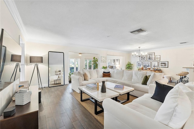 living room featuring a textured ceiling, crown molding, and a notable chandelier