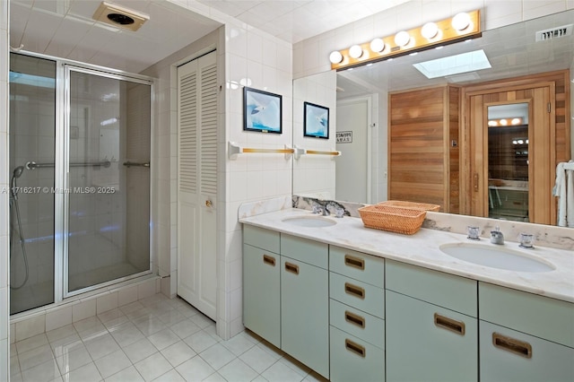 bathroom with vanity, a skylight, tile patterned floors, and an enclosed shower