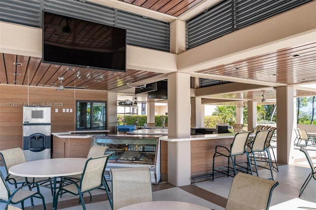 view of patio / terrace with ceiling fan, a bar, and a fireplace