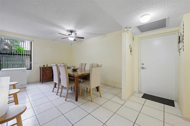 tiled dining area with ceiling fan and a textured ceiling