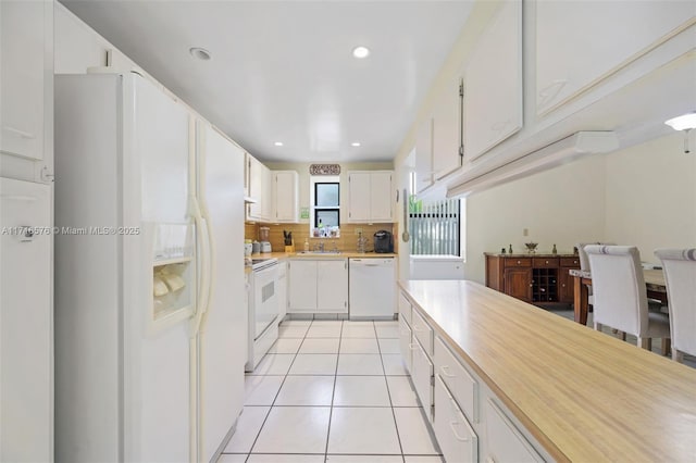 kitchen featuring white appliances, white cabinets, sink, decorative backsplash, and light tile patterned floors