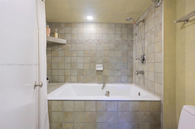 bathroom with toilet and tiled shower / bath