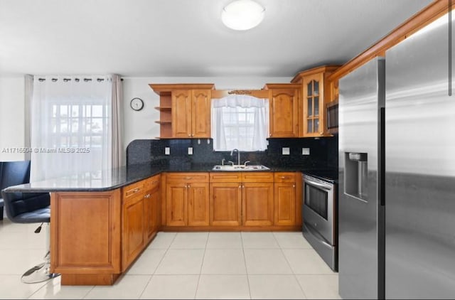 kitchen featuring sink, kitchen peninsula, dark stone countertops, decorative backsplash, and appliances with stainless steel finishes