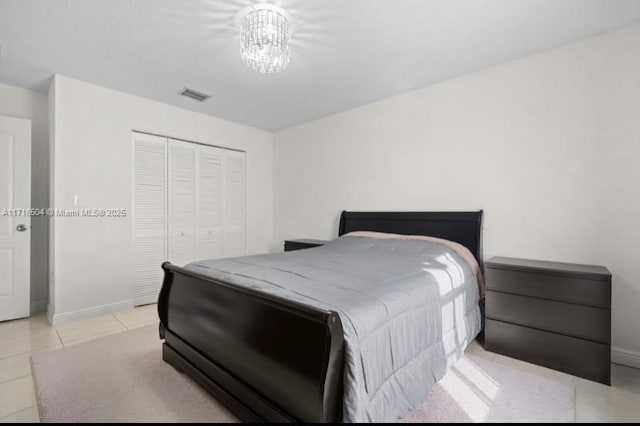 tiled bedroom with a notable chandelier and a closet