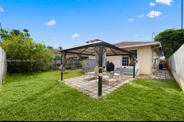 rear view of property featuring a lawn, a patio area, a gazebo, and a storage shed