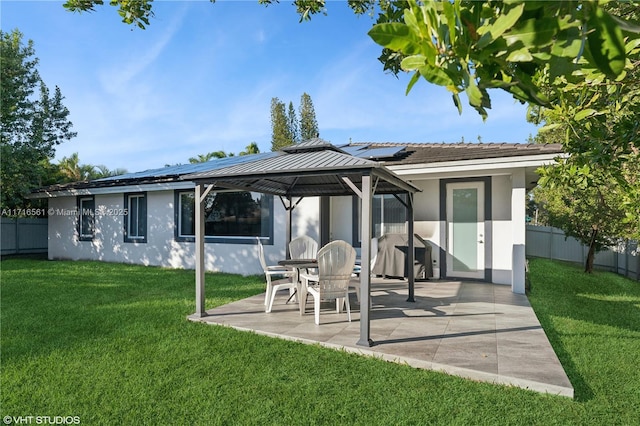 back of house featuring a yard, a patio, and solar panels