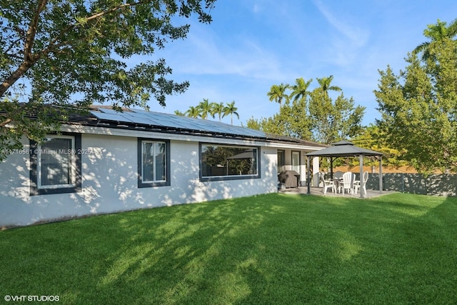 rear view of property with a gazebo, a yard, a patio, and solar panels